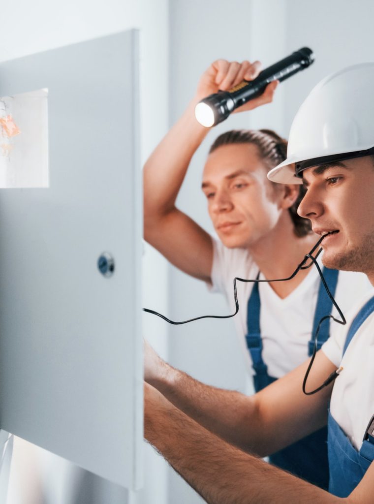 two-young-male-electricians-works-indoors-together-using-flashlight.jpg